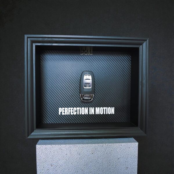 Automobilio raktelio meno paveikslas rėmelyje su anglies pluošto fonu ir užrašu „Perfection in Motion“