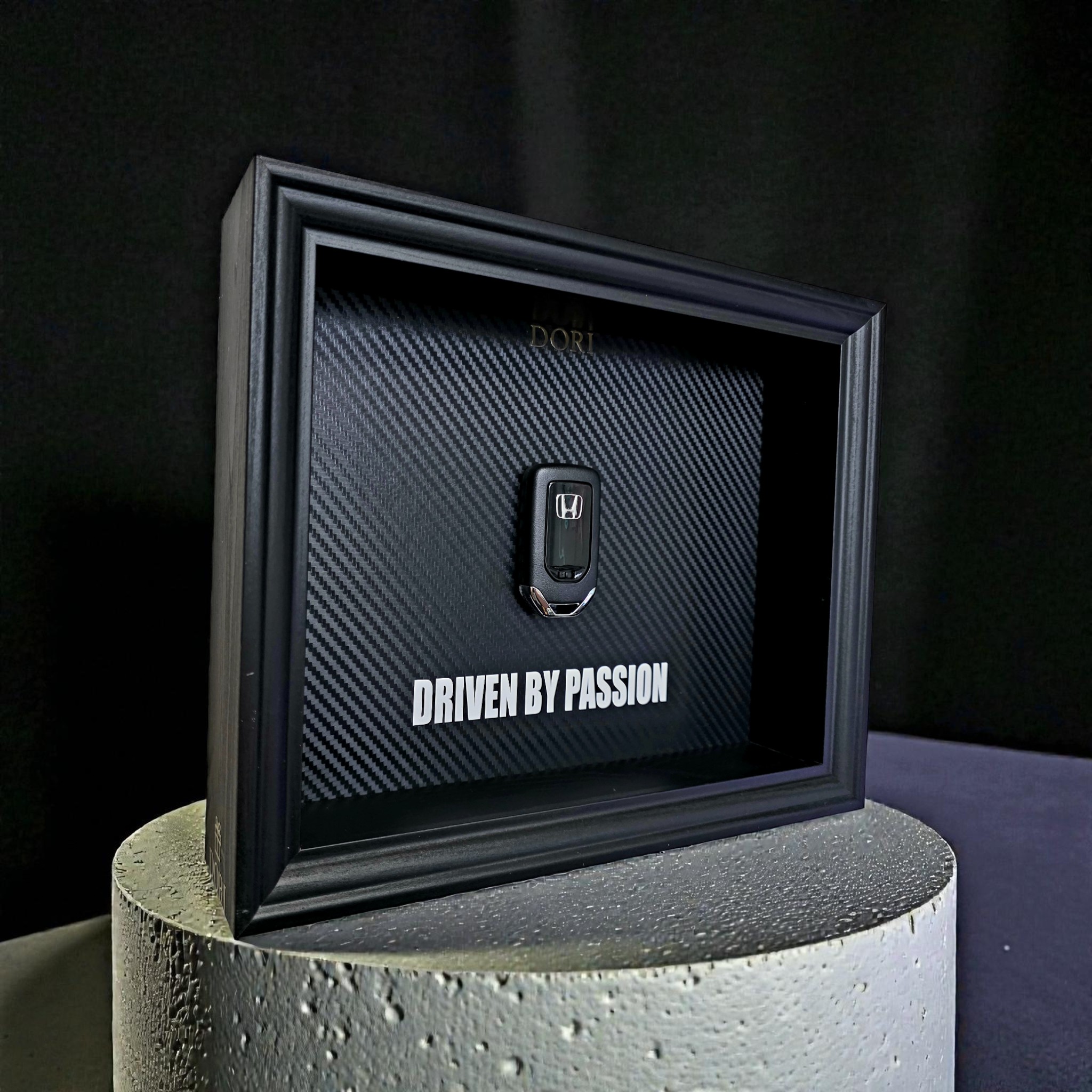 Automobilio raktelio dekoratyvinis paveikslas su anglies pluošto fonu ir užrašu „Driven by Passion“