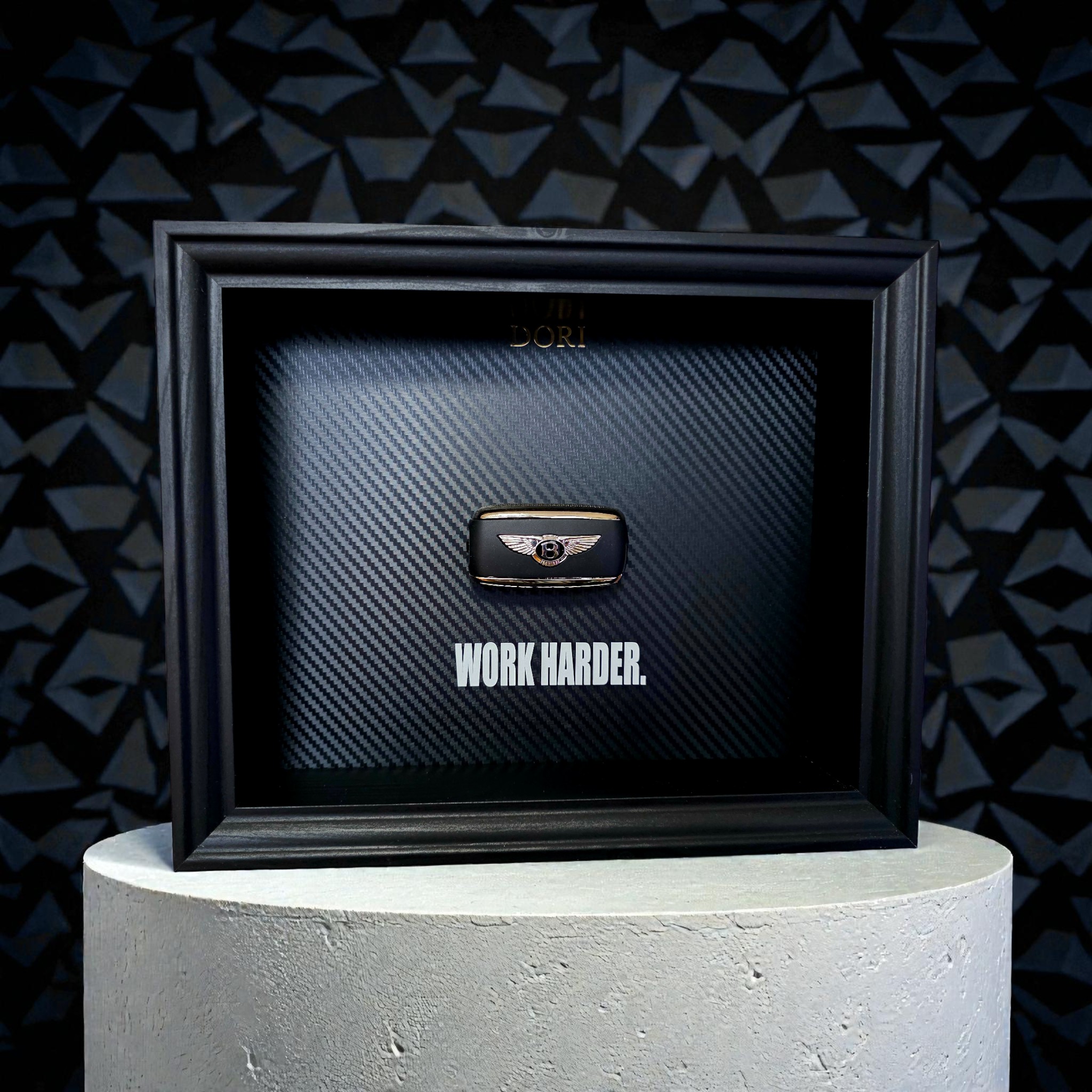 Automobilio raktelio dekoratyvinis paveikslas su anglies pluošto fonu ir užrašu „Work Harder“