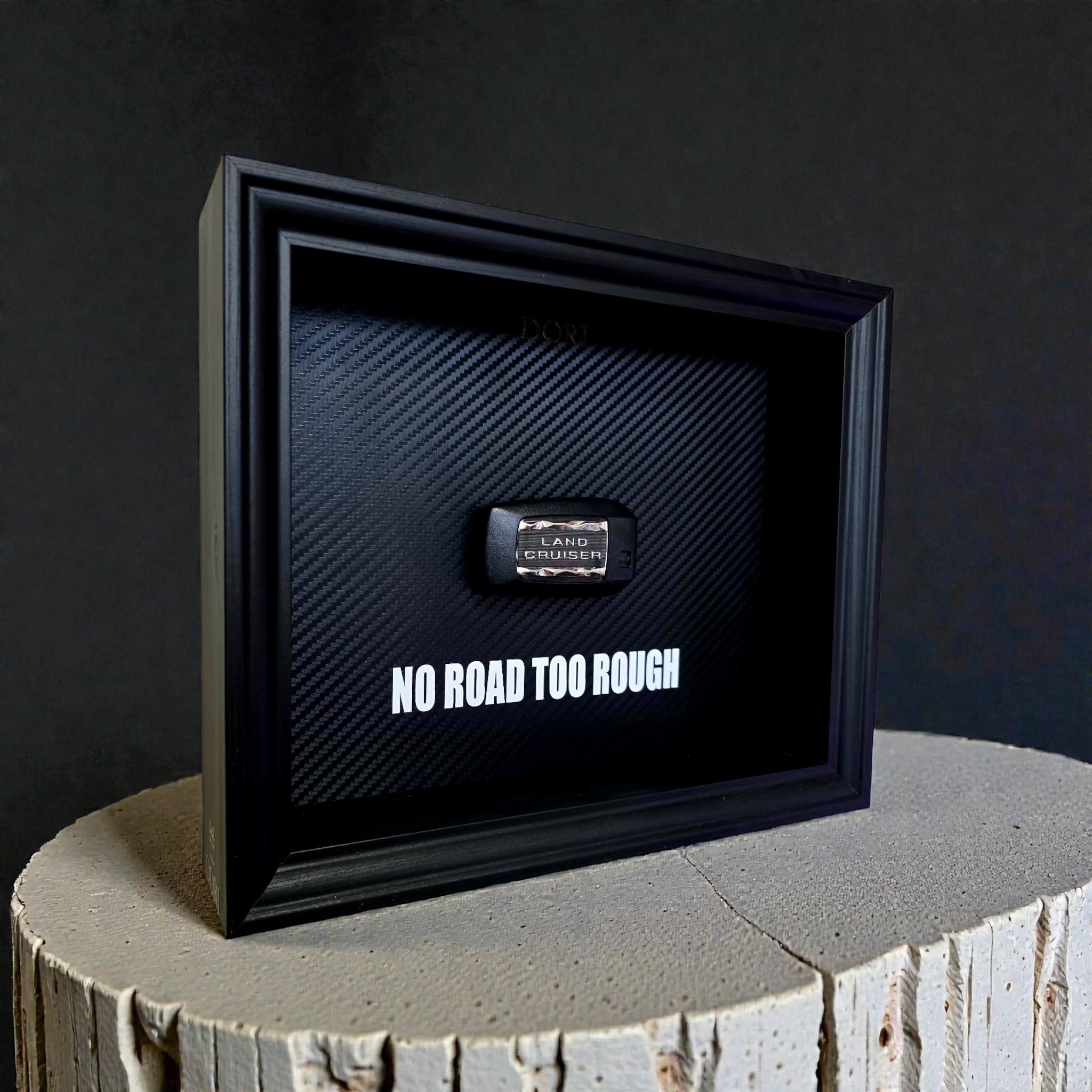Automobilio raktelio dekoratyvinis paveikslas su anglies pluošto fonu ir užrašu „No Road Too Rough“