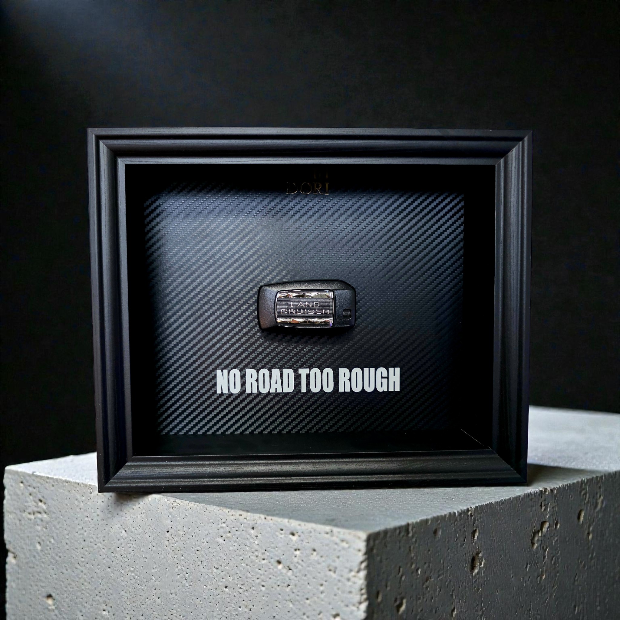 Automobilio raktelio dekoratyvinis paveikslas su anglies pluošto fonu ir užrašu „No Road Too Rough“