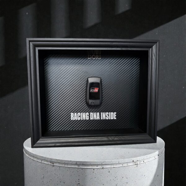 Automobilio raktelio dekoratyvinis paveikslas su anglies pluošto fonu ir užrašu „Racing DNA Inside“