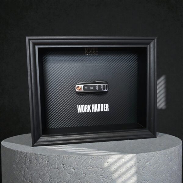 Automobilio raktelio dekoratyvinis paveikslas su anglies pluošto fonu ir užrašu „Work Harder“