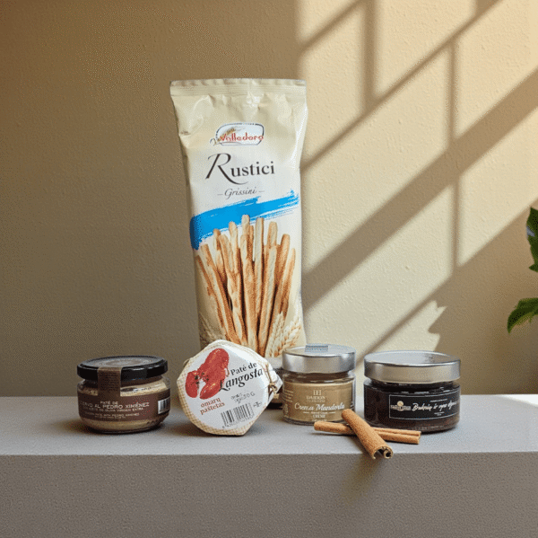 Tonavime šiltame fone fotografuotas DORI gurmaniškas rinkinys su italų grissini lazdelėmis, įvairiais premium paštetais ir pagardais, akcentuotas cinamono lazdelėmis.