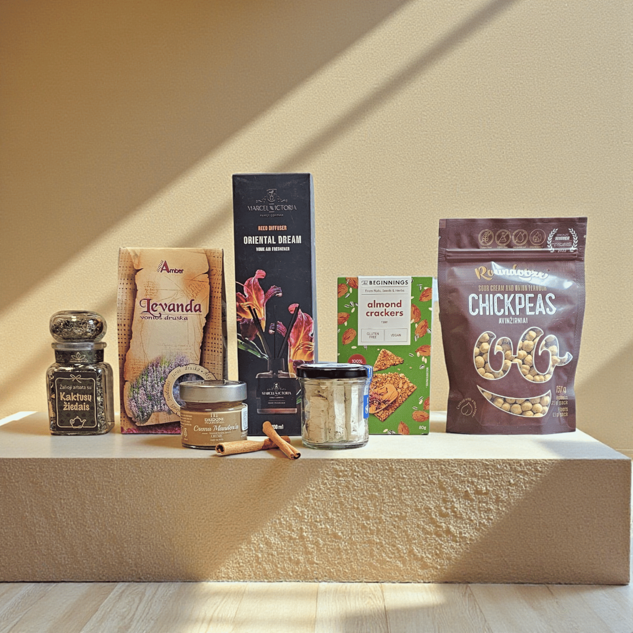 DORI gurmaniškas rinkinys su levandų druska, difuzoriumi, kremais ir traškučiais, fotografuotas šiltame minimalistiniame fone.