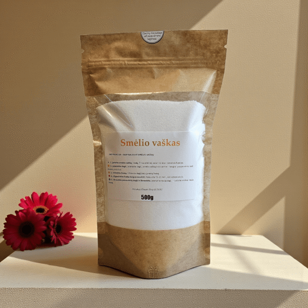 Birus smėlio vaškas 500 g kraft maišelyje su etikete, nufotografuotas šiltame minimalistiniame fone su dekoratyvine gėle.