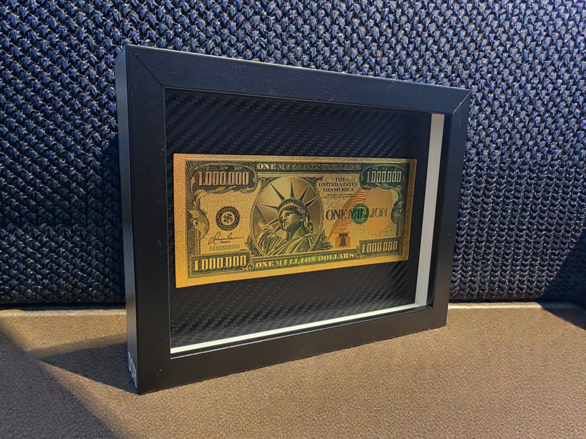 Auksinis ir žalias „One Million“ paveikslas juodame rėme