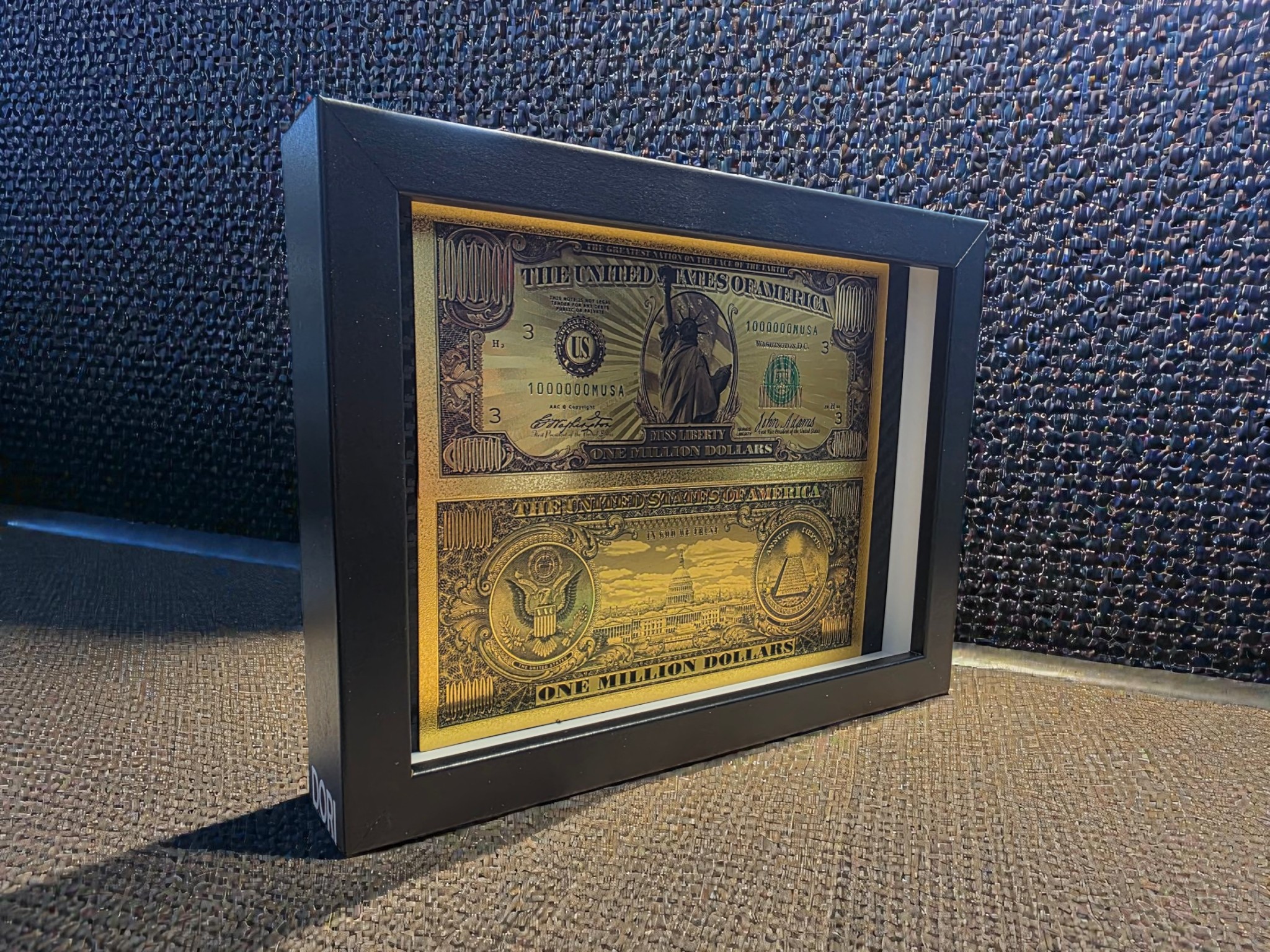 Auksinis „One Million Dollars“ paveikslas juodame rėme