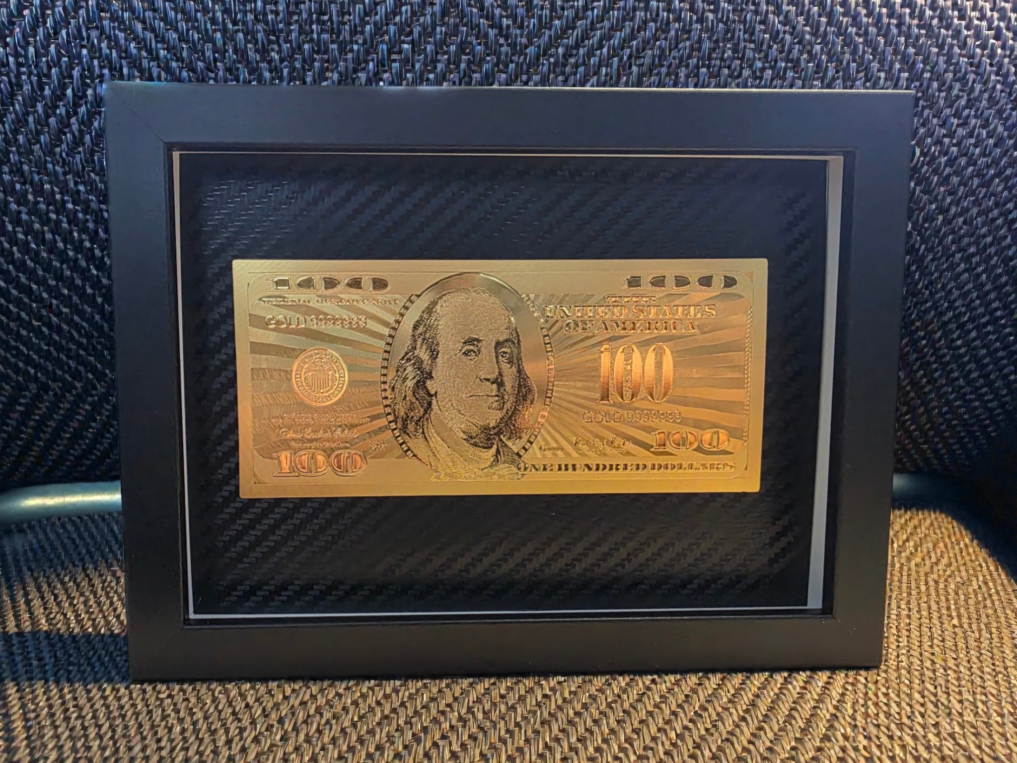 Pilnai auksinis 100 dolerių paveikslas juodame rėme su karbono fonu