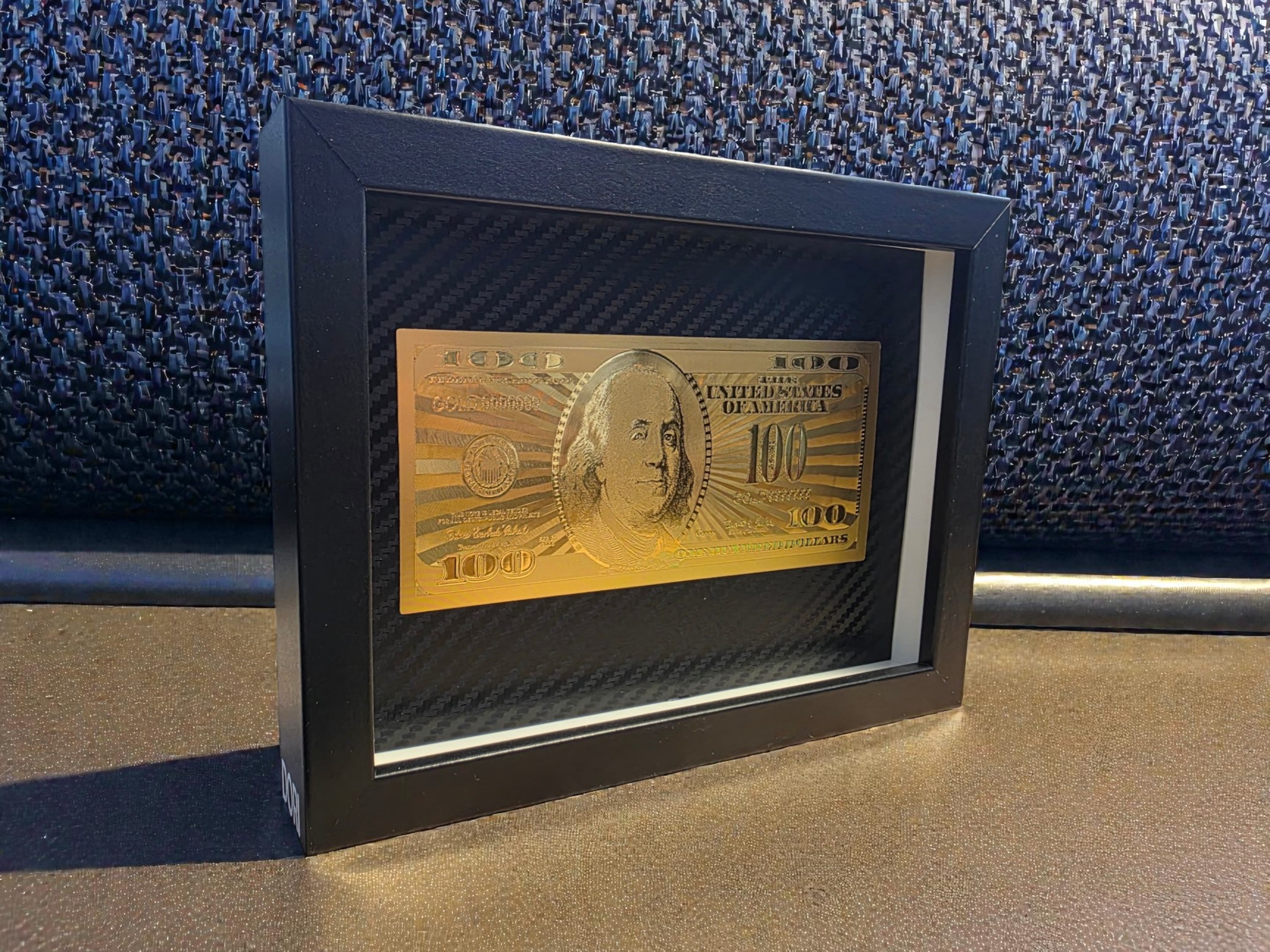 Pilnai auksinis 100 dolerių paveikslas juodame rėme su karbono fonu